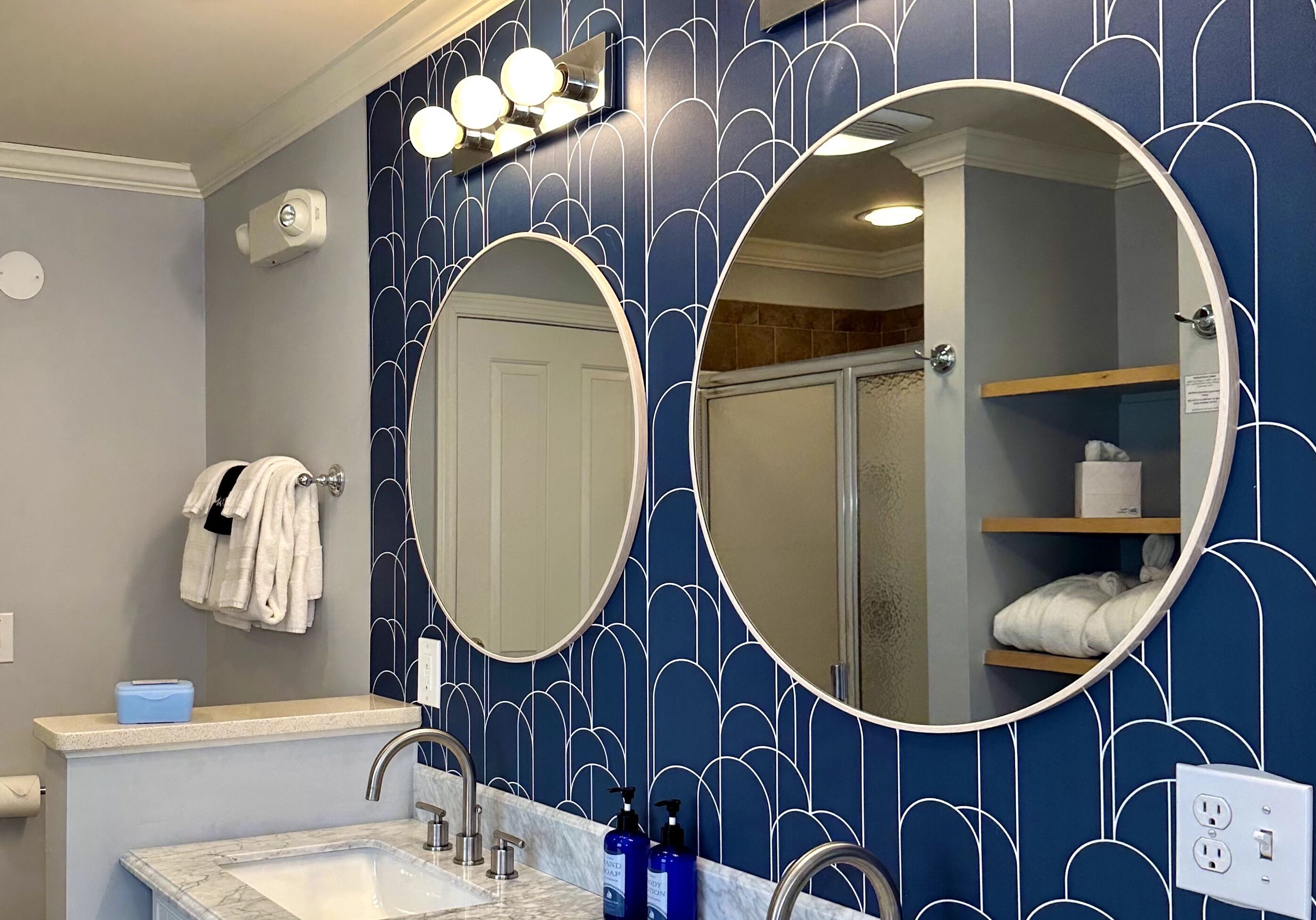 A bathroom with two large mirrors, a sink, and a towel rack.