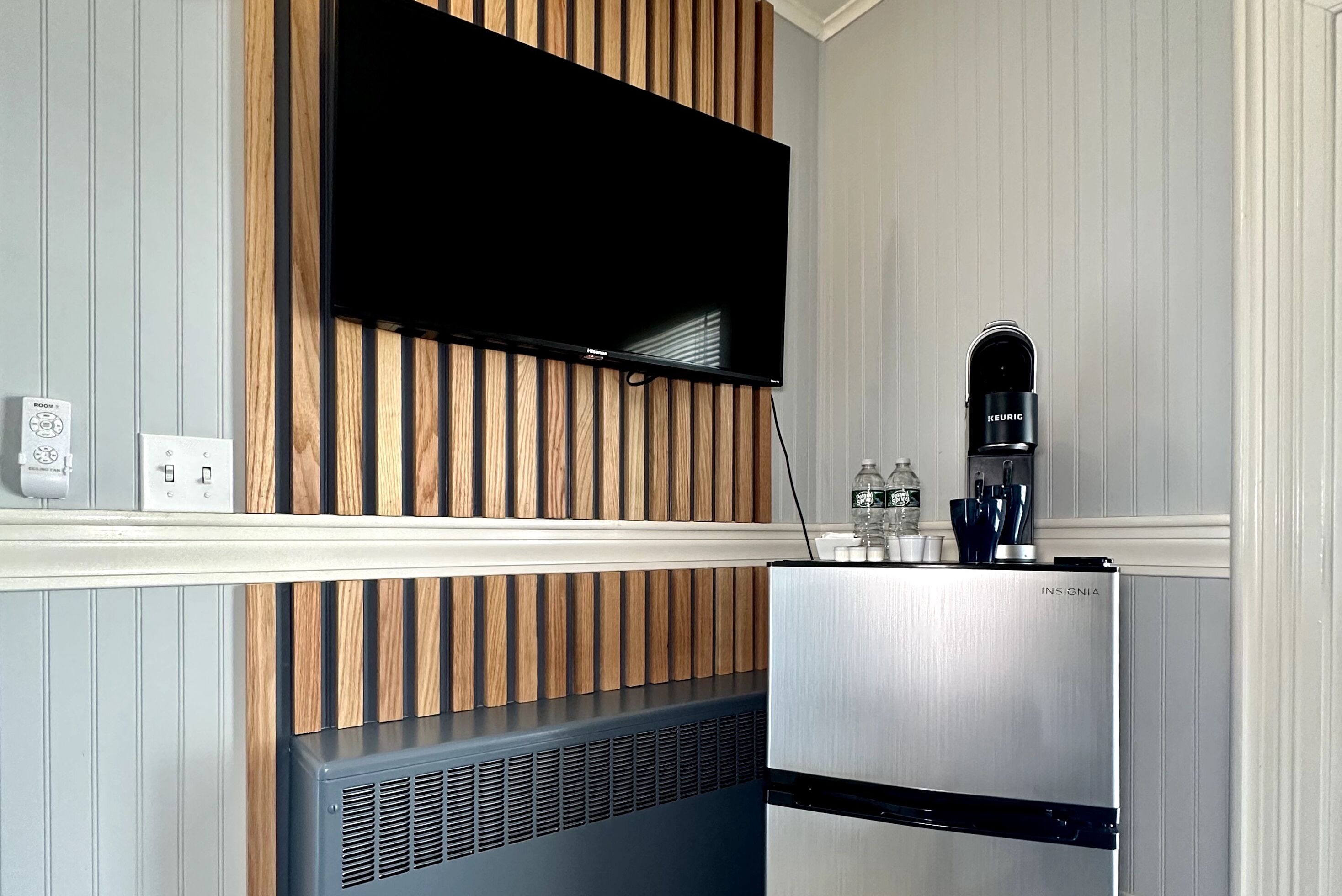A modern kitchen with a built-in TV, a stainless steel refrigerator, and a coffee machine.
