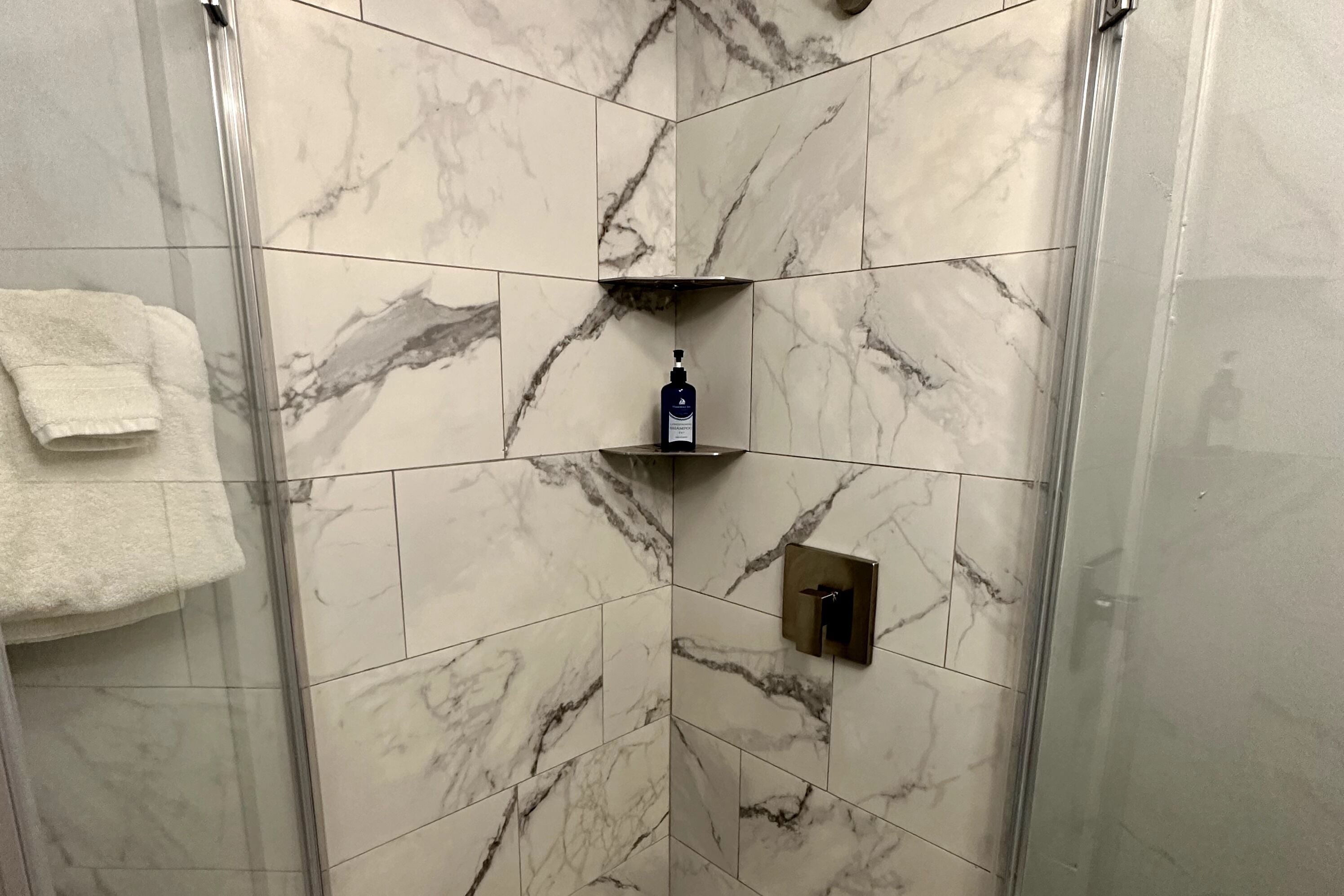 A shower area with marble tiles and a glass enclosure.