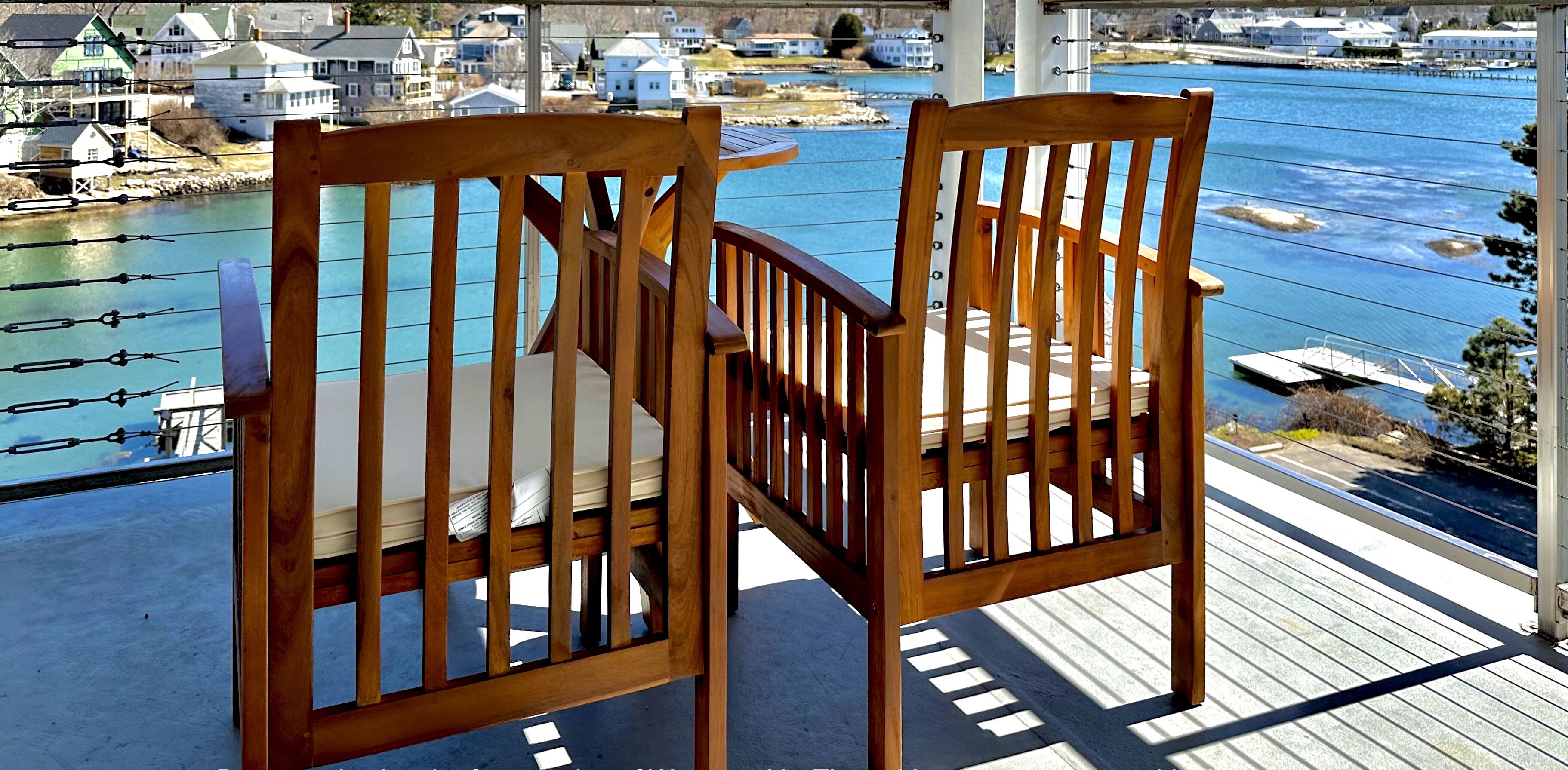 Two wooden chairs with a view of a marina and houses in the background.
