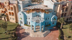 Ein großes, mehrgeschossiges Hotel mit einem markanten blau-beigen Farbdesign, das einen zentralen Innenhof mit Brunnen und Außenbereich zum Verweilen bietet.
