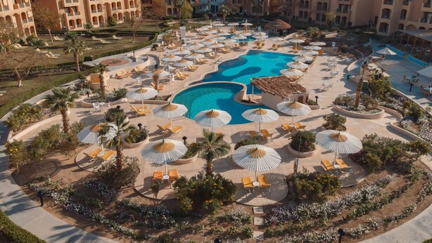 Ein Resort mit einem zentral gelegenen Schwimmbad, Liegestühlen und Sonnenschirmen.