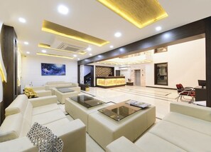 A modern hotel lobby with a reception desk, seating area, and a staircase. - The Rigel (Agra)