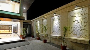 Un espace extérieur agrémenté d’une façade de bâtiment moderne, ornée de motifs de feuilles décoratives et de plantes en pot.