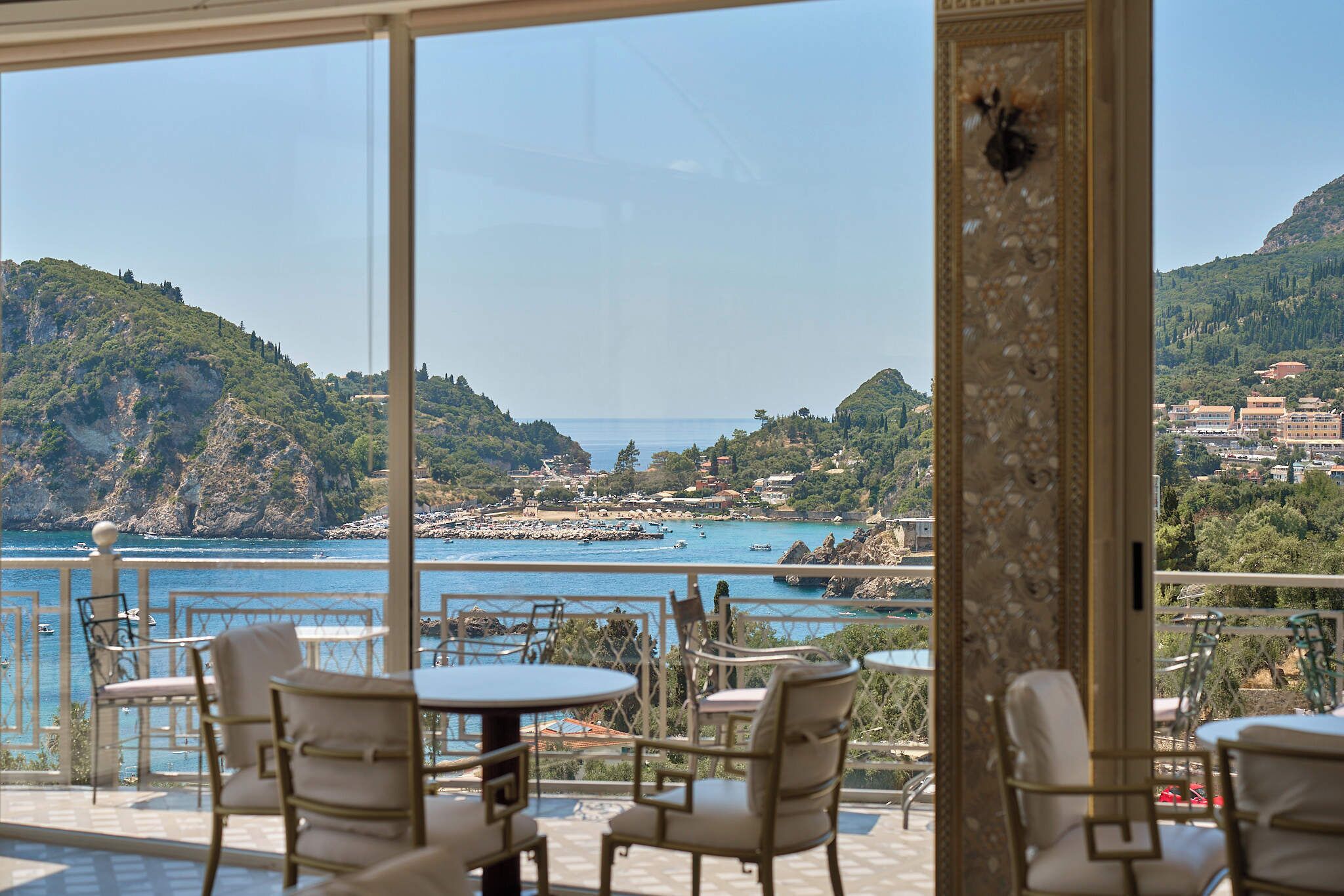 A terrace with outdoor seating overlooking a coastal town and the sea.