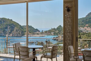 A terrace with outdoor seating overlooking a coastal town and the sea. - Paleokastritsa Palace (Corfu)