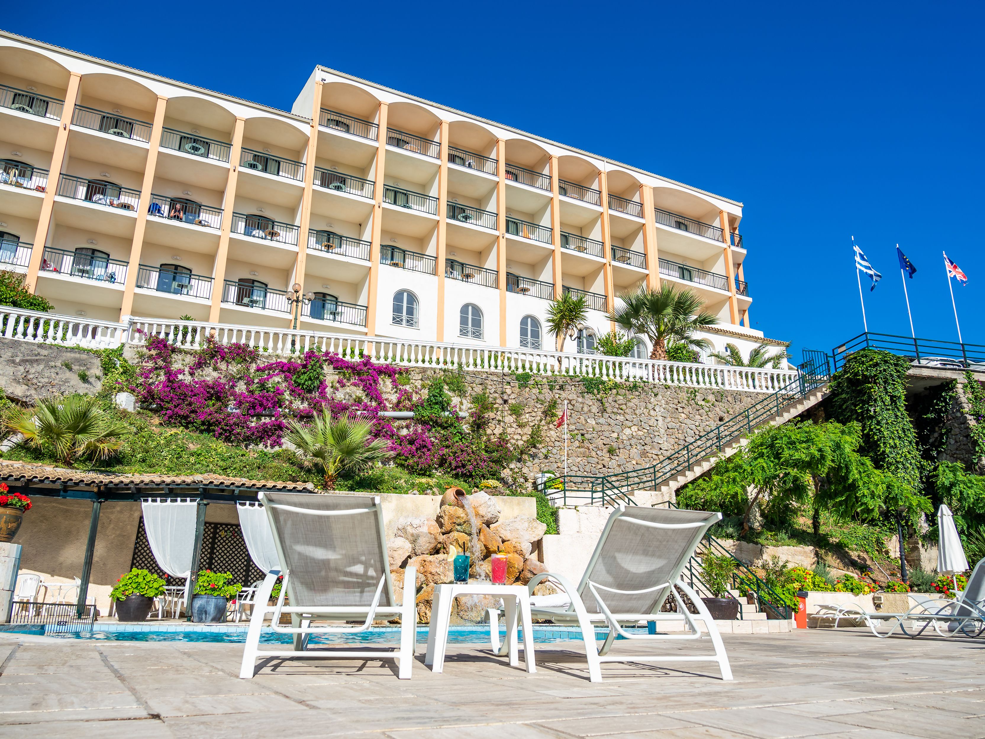 A hotel with multiple balconies, a swimming pool, and outdoor seating.