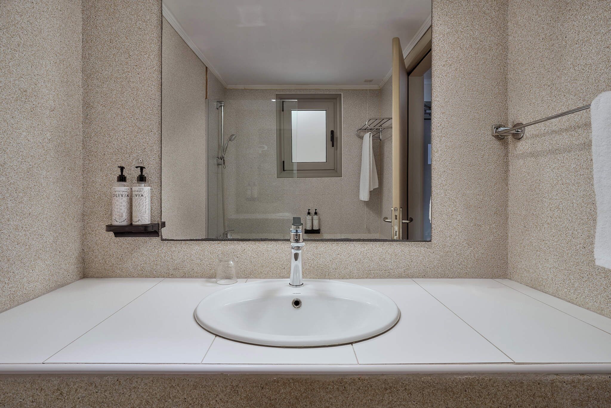 A bathroom with a white sink, a mirror, and a shower.
