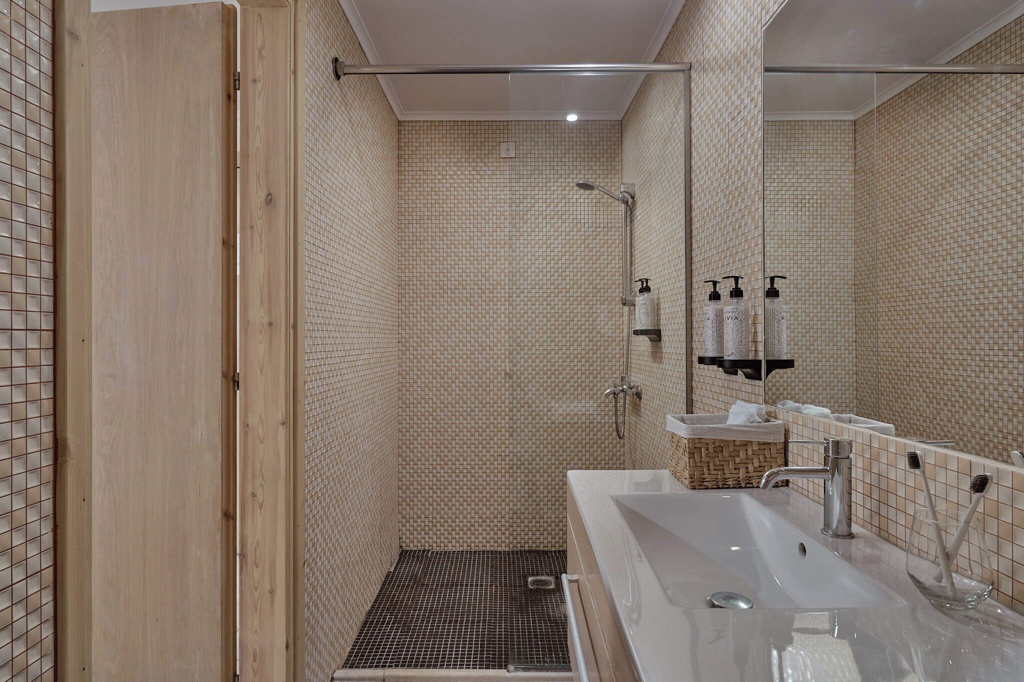 A modern bathroom with a shower, a sink, and a mirror.