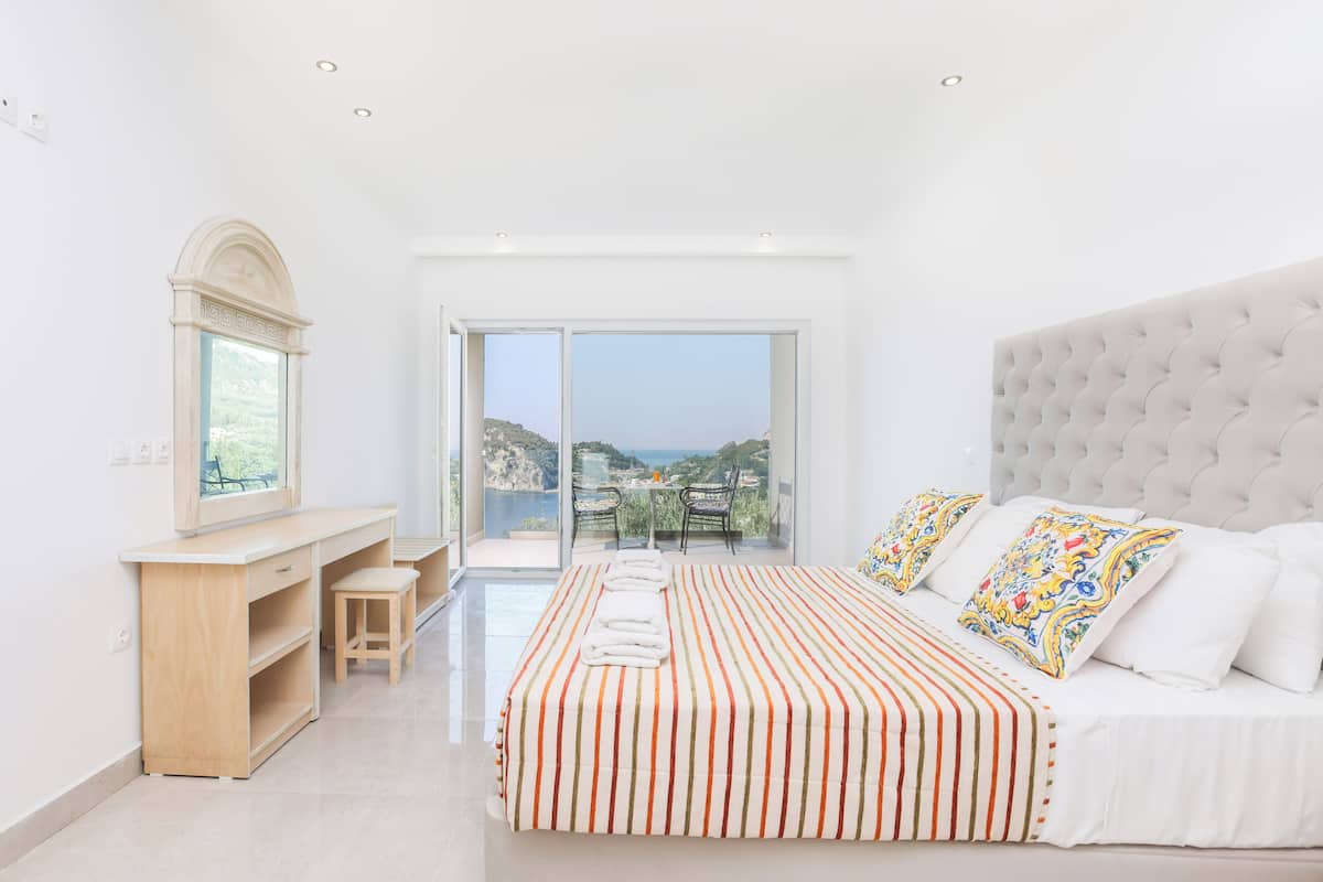 Une chambre avec un grand lit, un bureau et une vue sur la mer.