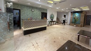 A hotel lobby with a reception desk, a clock, a staircase, and a mural on the wall. - Hotel Idea Inn (Agra)