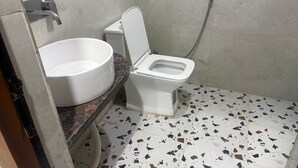 A bathroom with a white toilet, a white sink, and a shower. - Hotel Idea Inn (Agra)
