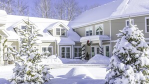 A two-story house with a snow-covered roof and a front porch. - On The River Inn (Woodstock)