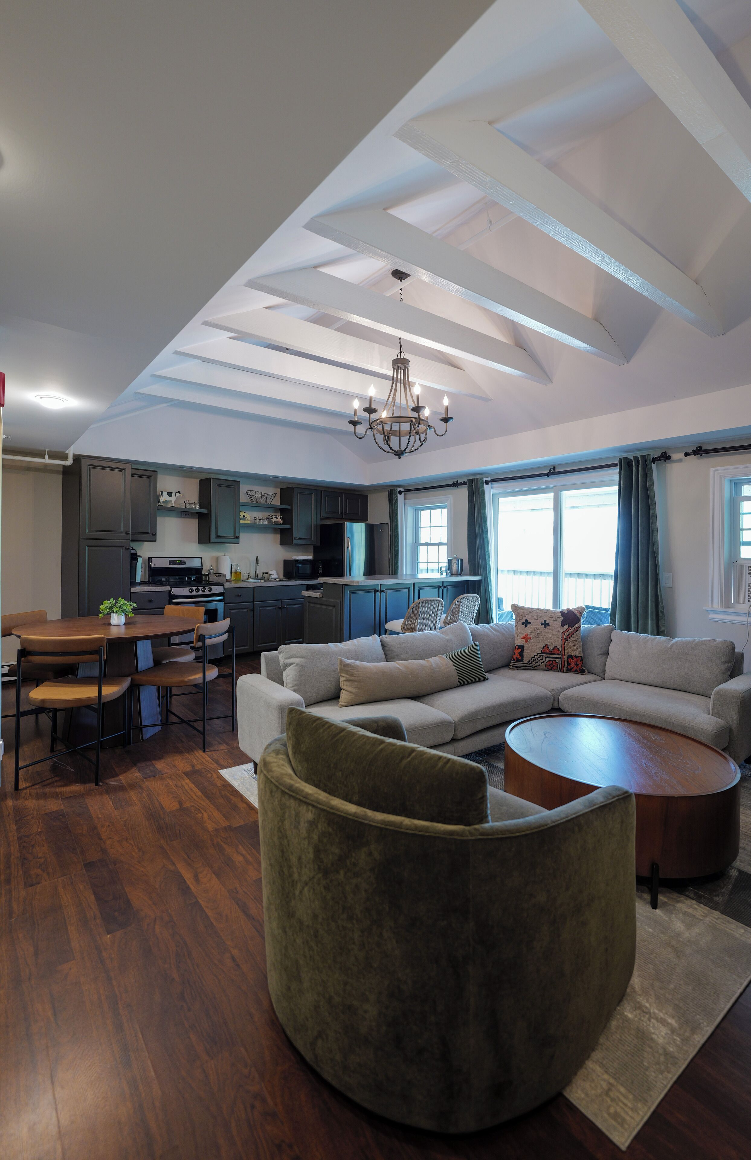 A modern living room with a sectional sofa, a round coffee table, and a dining area with a wooden table and chairs.
