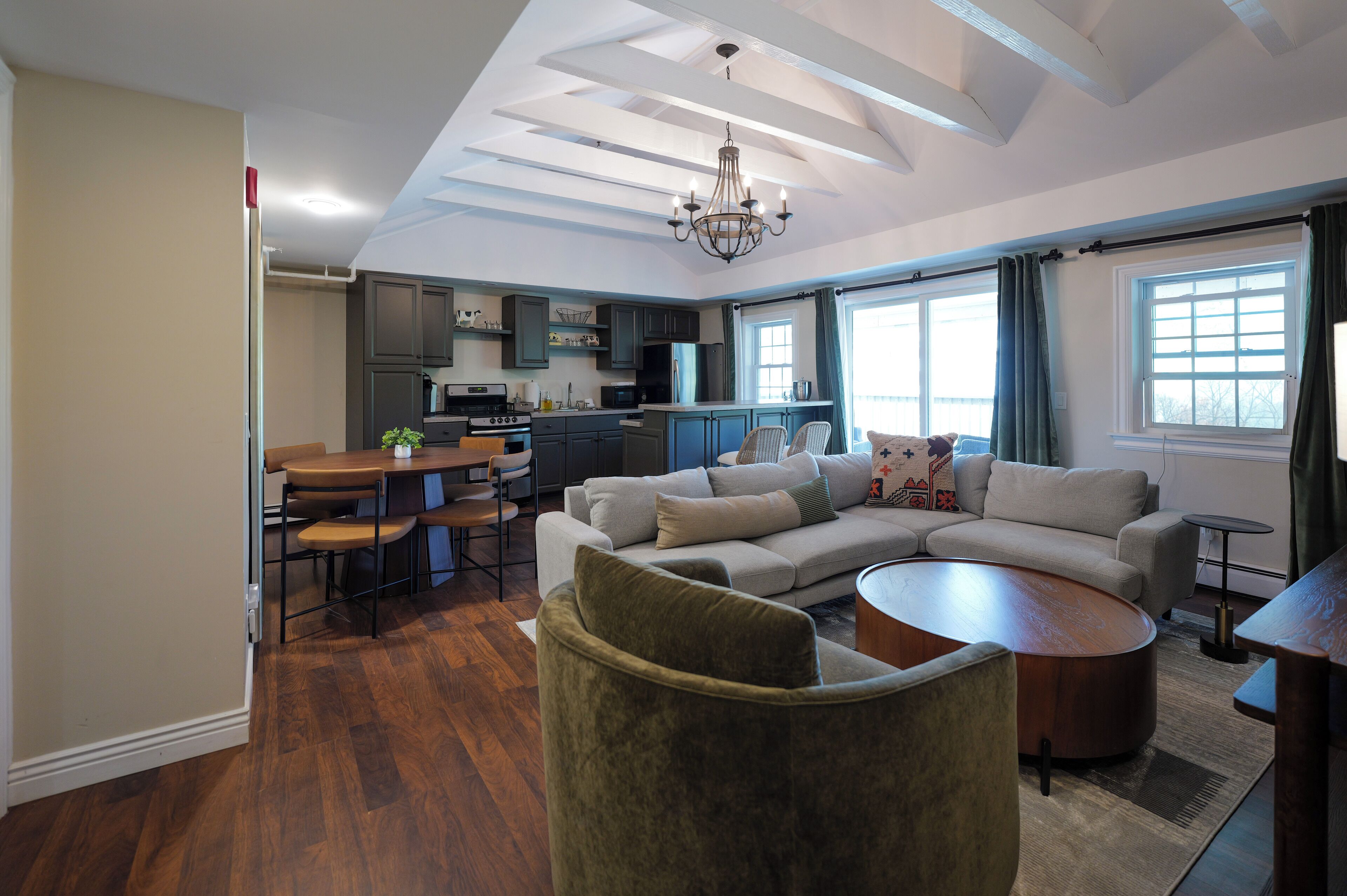 A modern living room with a sectional sofa, a round coffee table, and a dining area with a table and chairs.