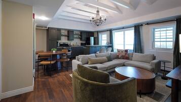 A modern living room with a sectional sofa, a round coffee table, and a dining area with a table and chairs.