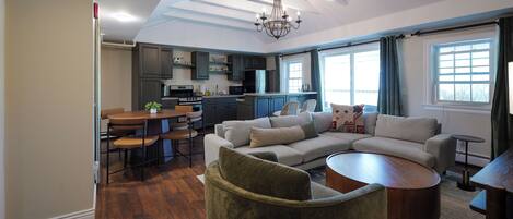 A modern living room with a sectional sofa, a round coffee table, and a dining area with a table and chairs.