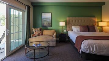 A hotel room with a bed, a sofa, a coffee table, and a painting on the wall.