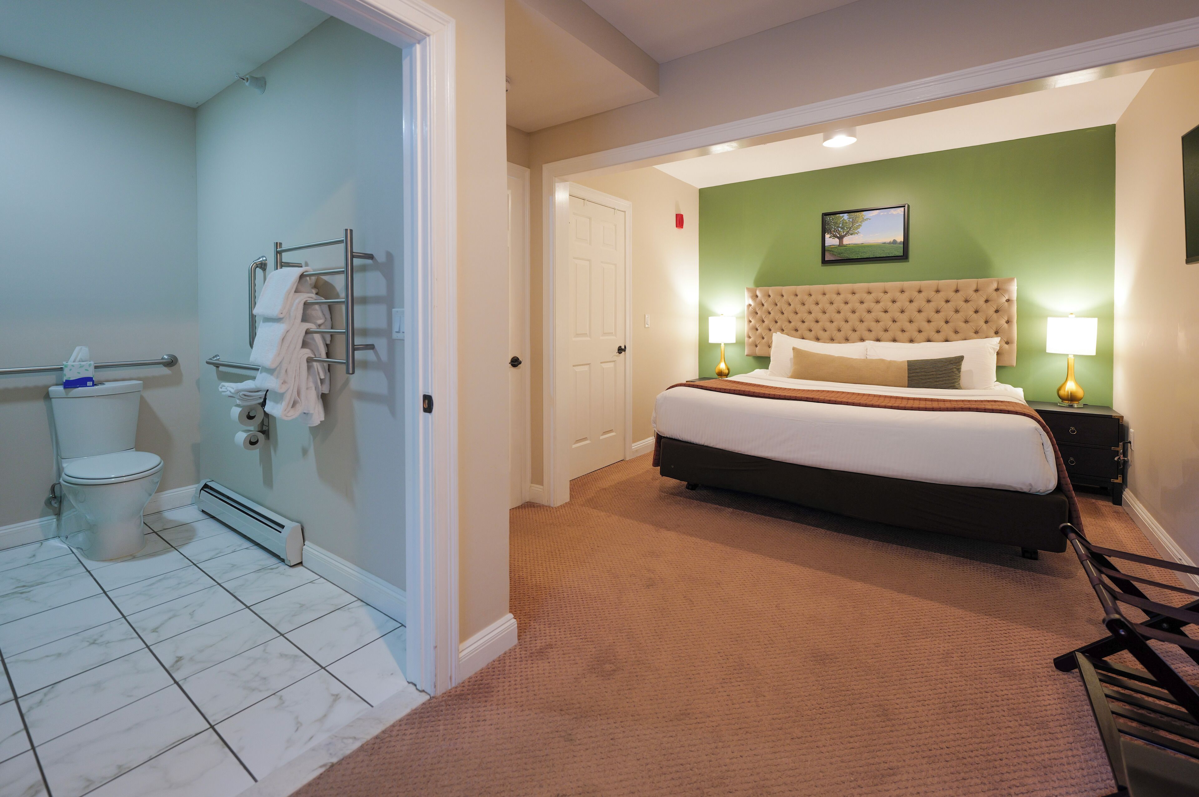 Ein Hotelzimmer mit Bett, Bad und grüner Wand.