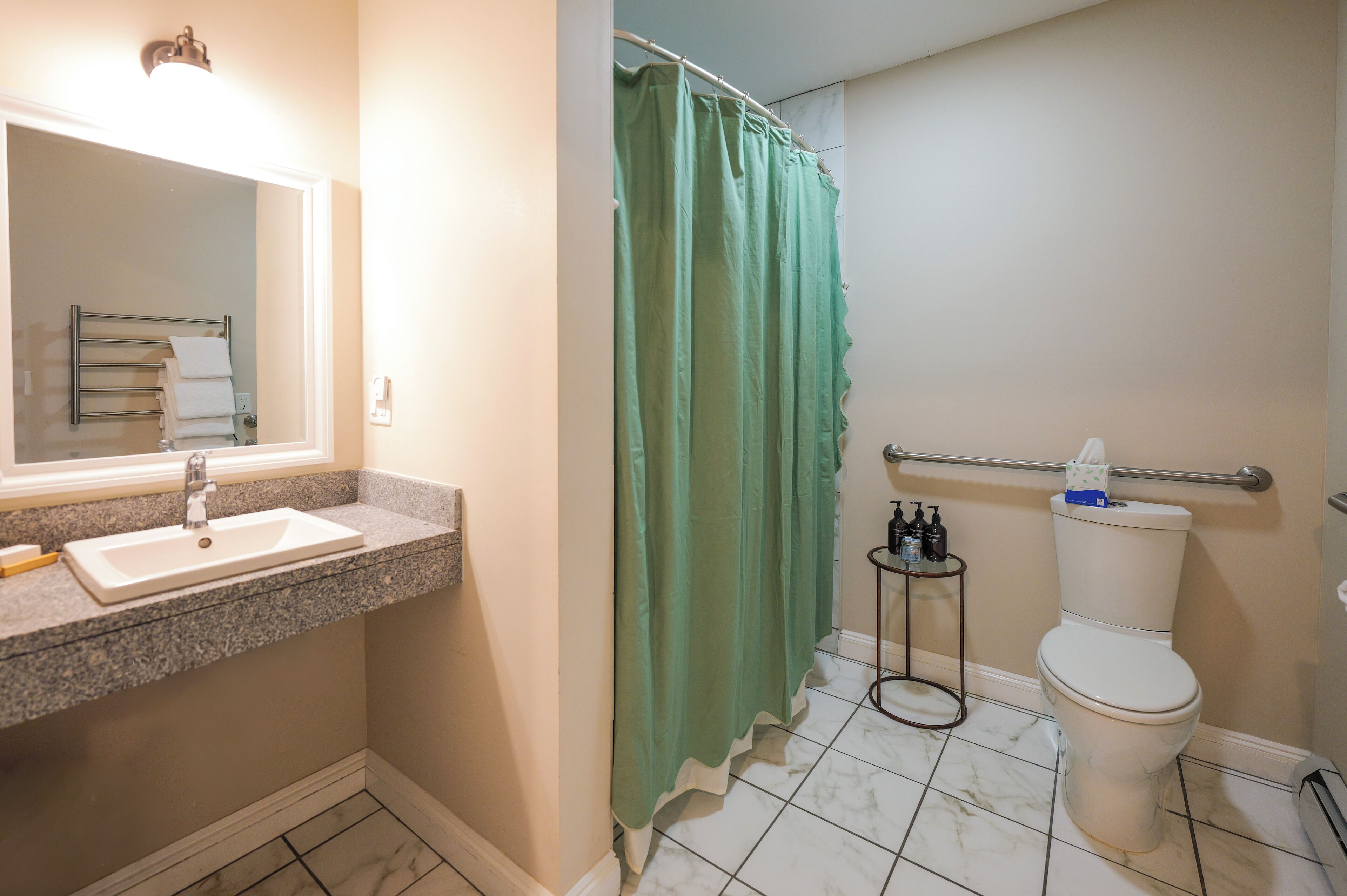 Een badkamer met een wastafel, spiegel, toilet en een groene douchegordijn.