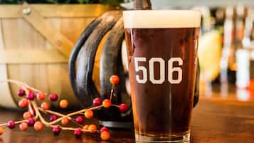 A glass of beer with the number 506 on it, placed on a wooden surface with a blurred background.