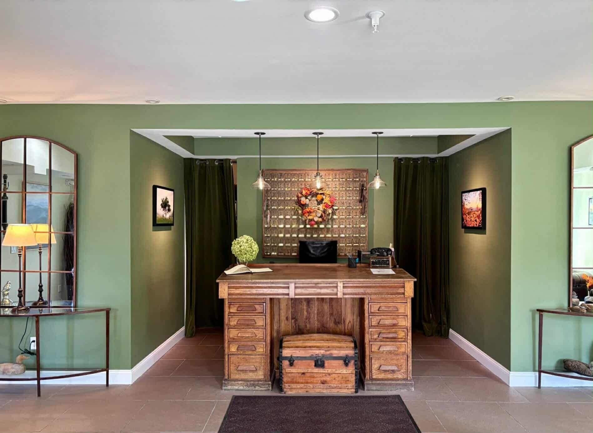 A room with a wooden desk, a mirror, and a decorative wall panel.