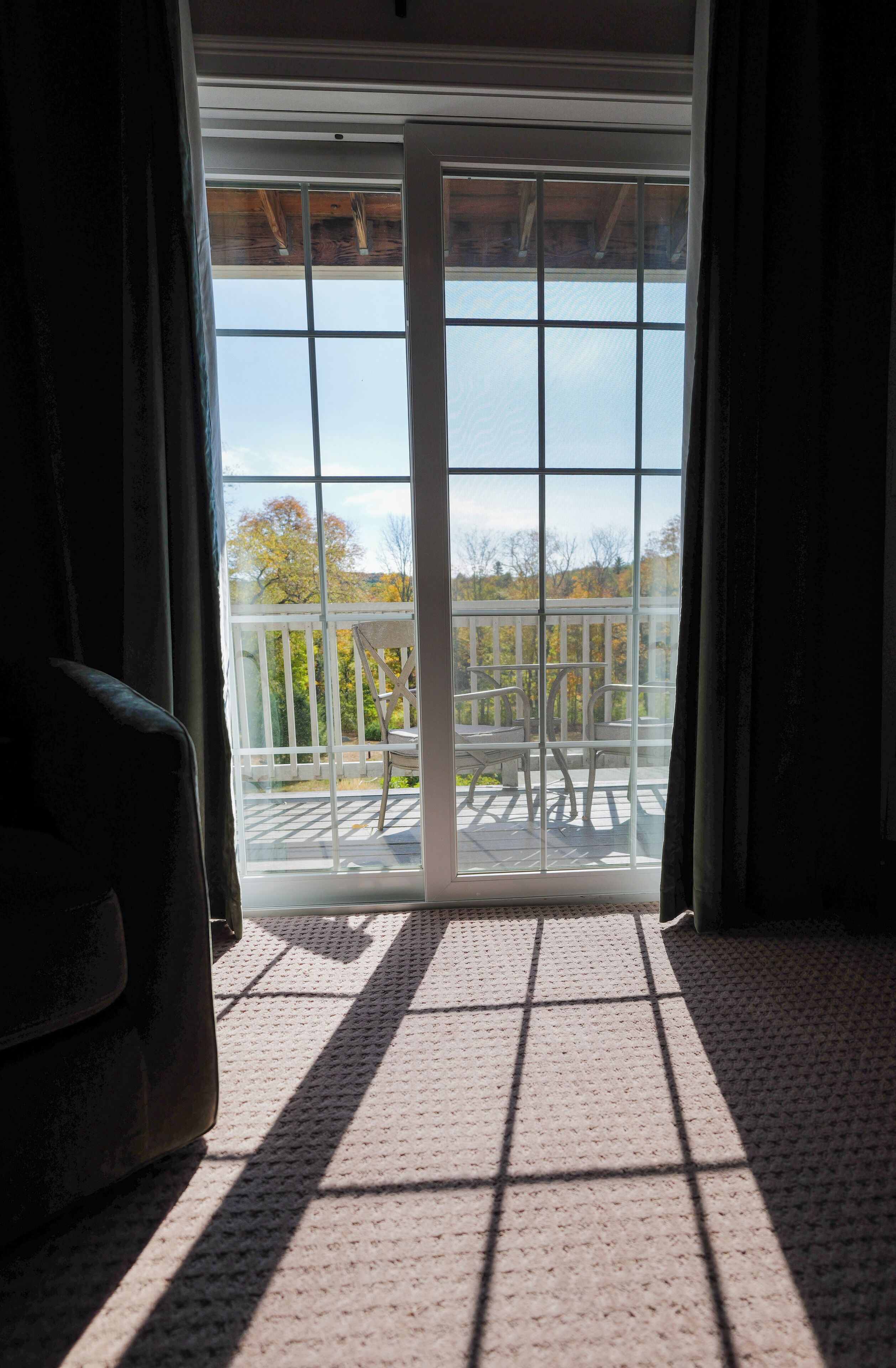 A room with a large sliding glass door leading to an outdoor deck with a view of trees and a clear sky.