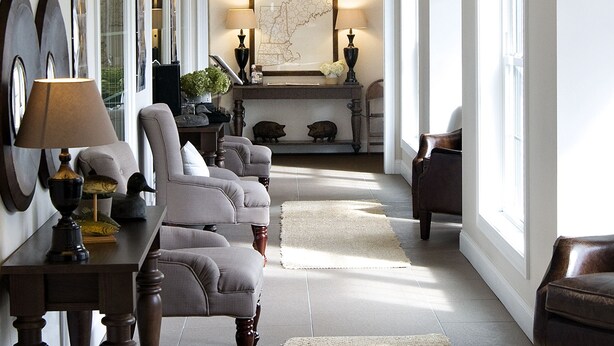 A spacious living room with a chandelier, multiple armchairs, a coffee table, and a rug. - On The River Inn (Woodstock)