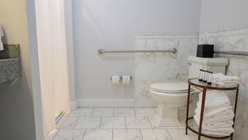 A bathroom with a shower, toilet, and a towel rack.