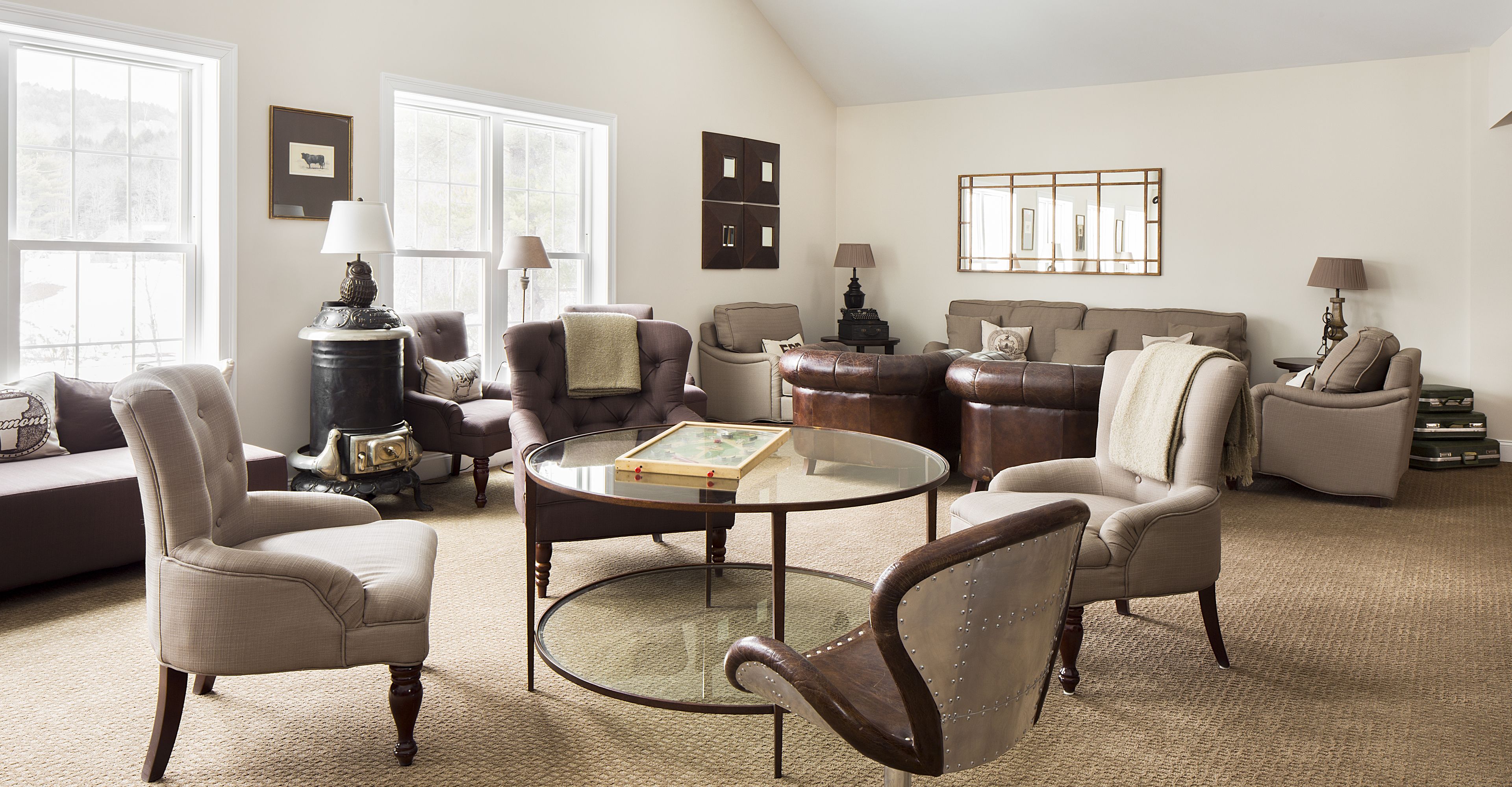 A spacious living room with a high ceiling, a glass coffee table, and multiple seating options including armchairs and a sofa.