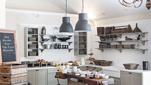 A kitchen with white tiled backsplash, wooden crates, and hanging pendant lights. - On The River Inn (Woodstock)