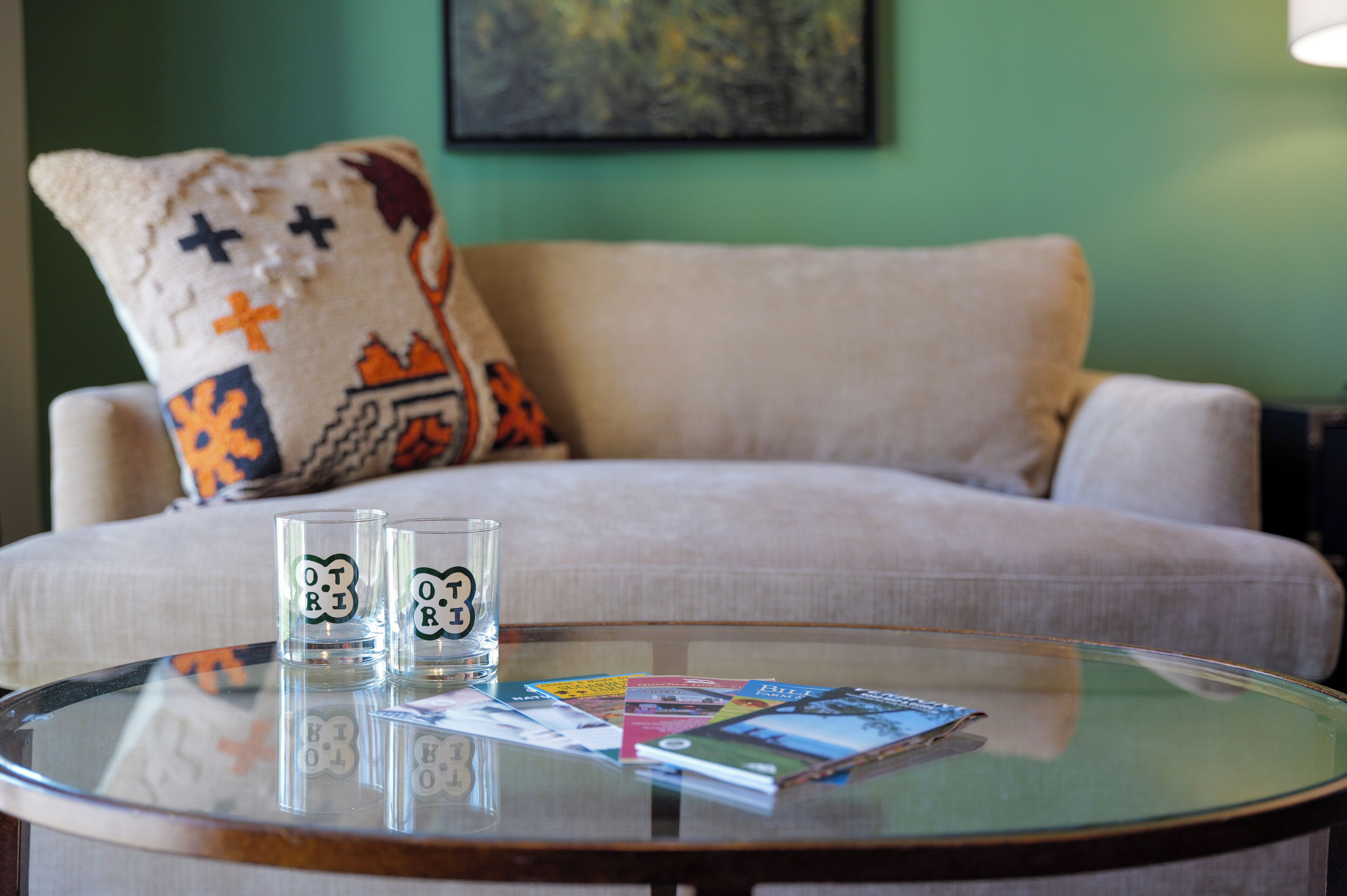 A round glass table with two glasses and a magazine.
