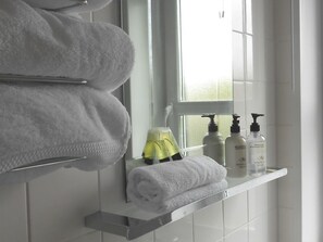 A bathroom with white towels, a mirror, and toiletries on a shelf. - The Kenbridge Hotel (Castle Douglas)