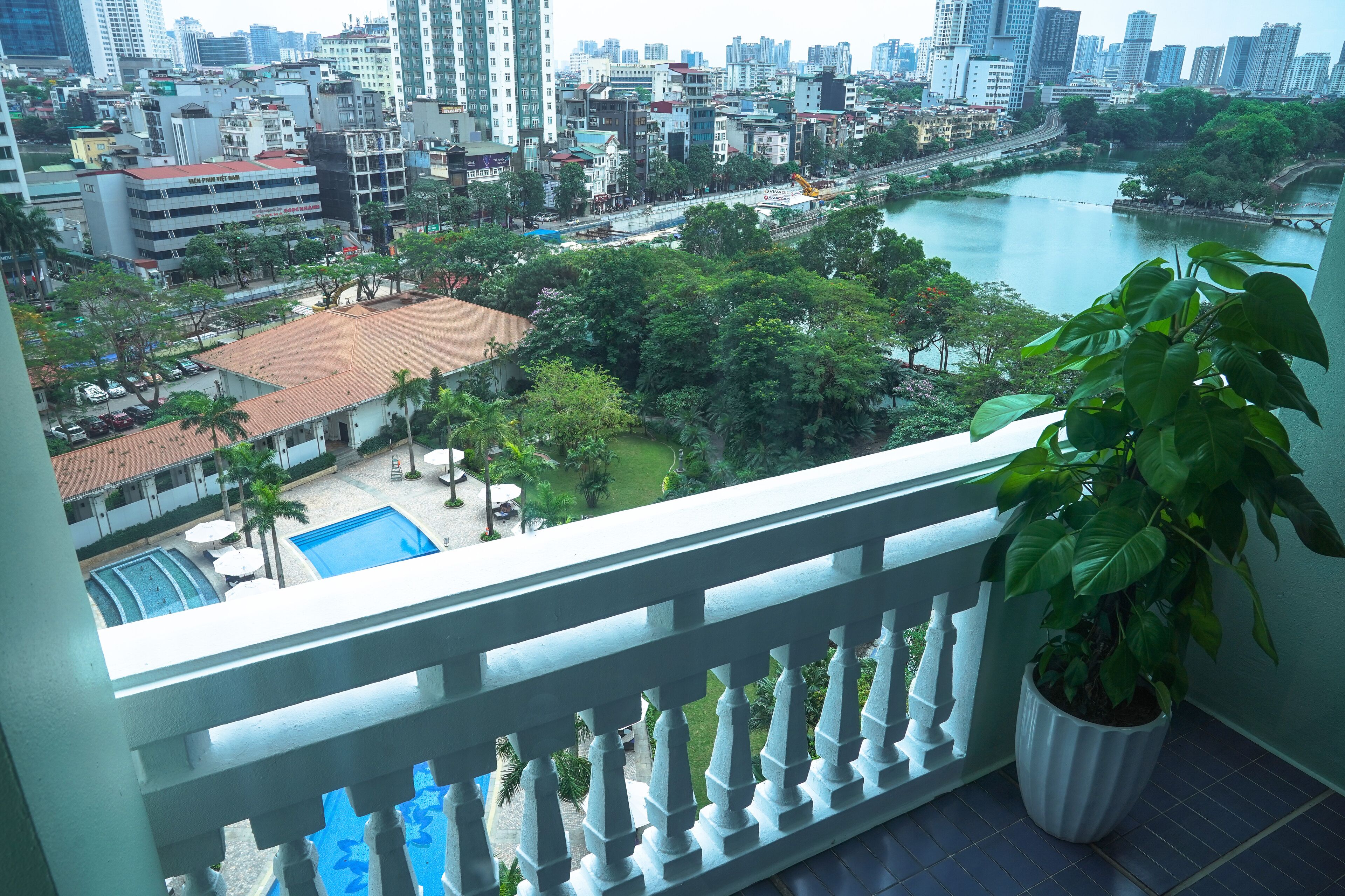 Un balcón con vistas a un paisaje urbano, una piscina y un río.