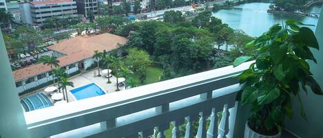 Un balcón con vistas a un paisaje urbano, una piscina y un río.