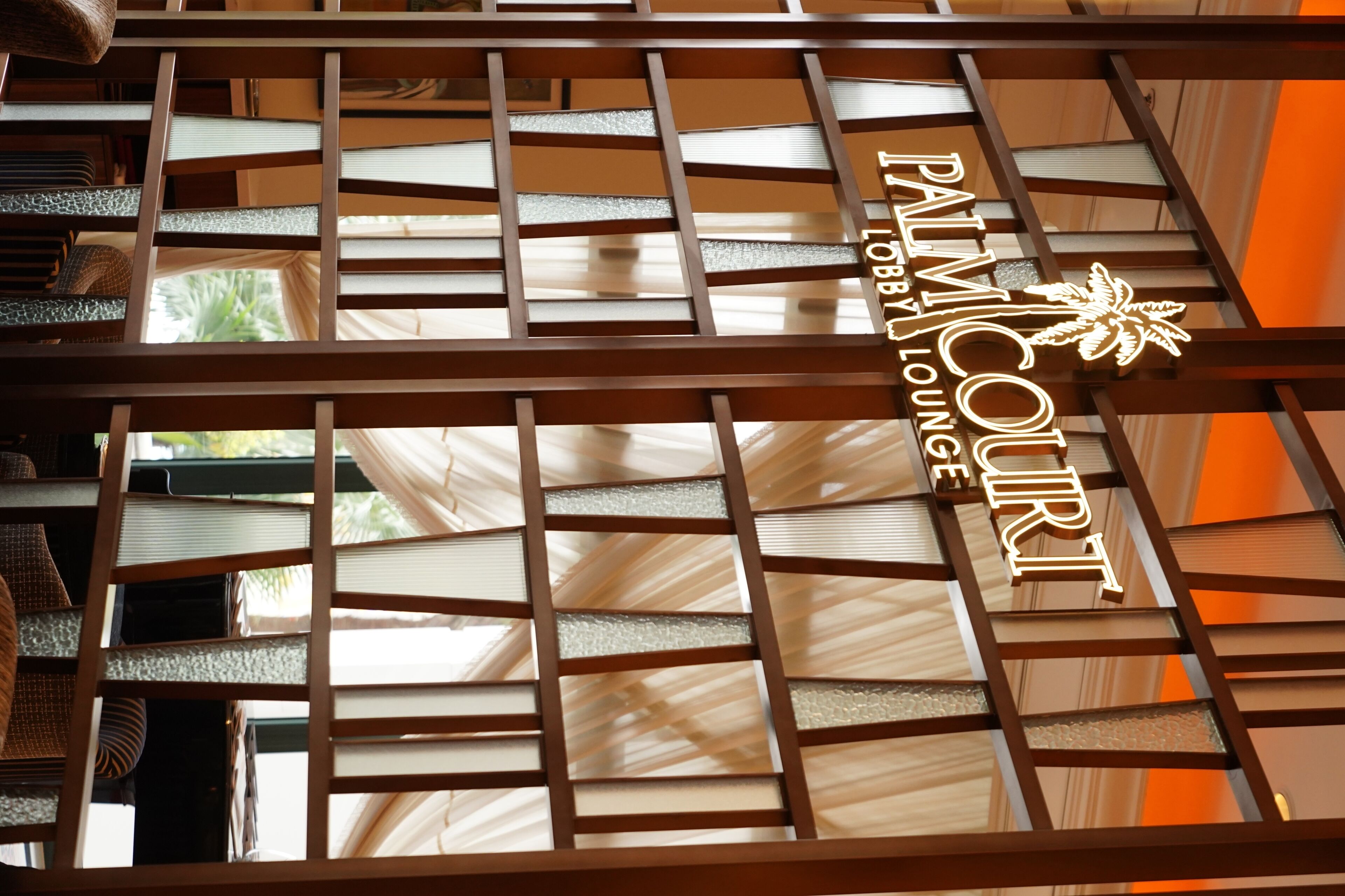 Un letrero con el texto 'PALMCOURT LOBBY LOUNGE' y un diseño de palmera.