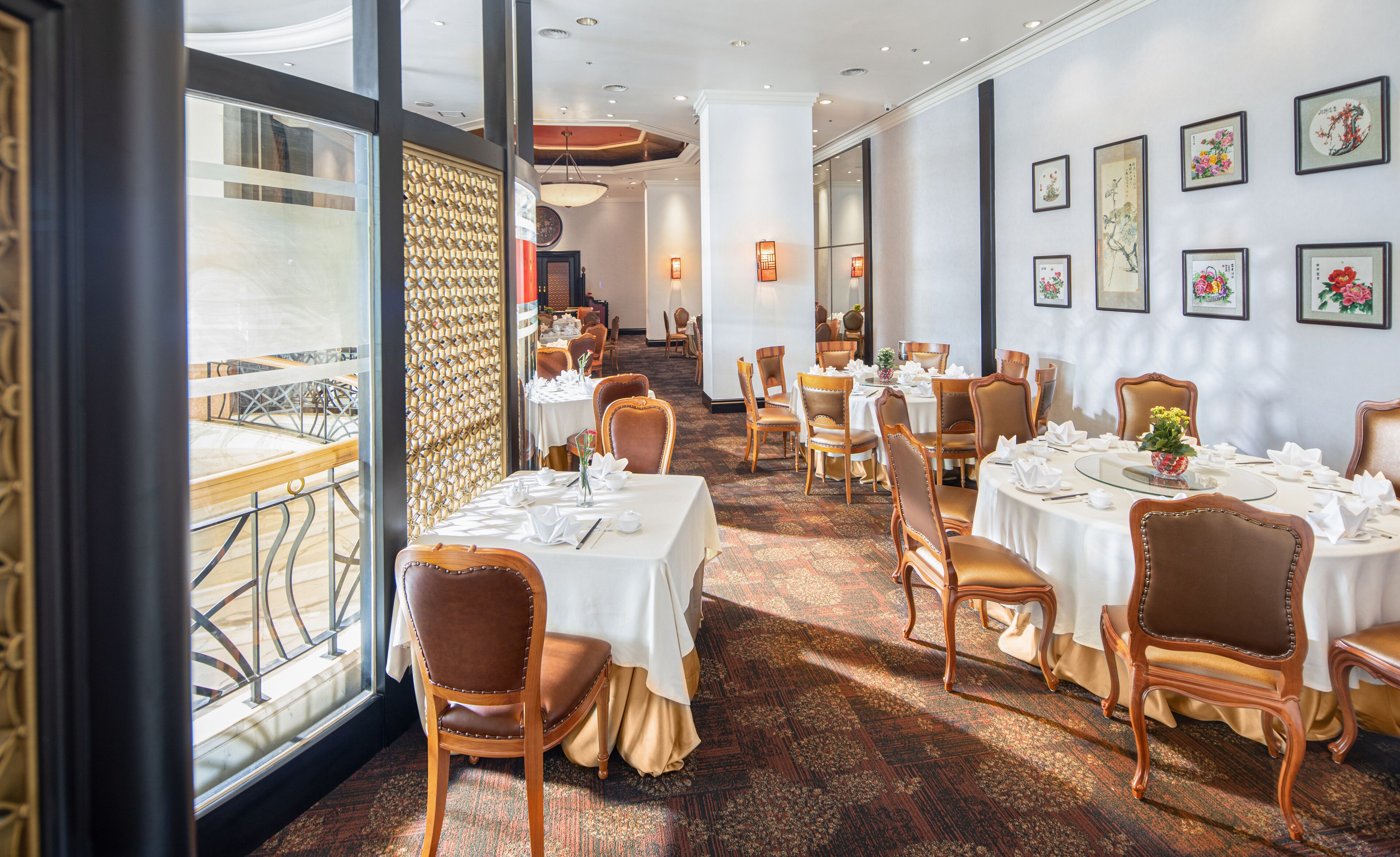 Un restaurante con mesas redondas, sillas y una alfombra estampada.