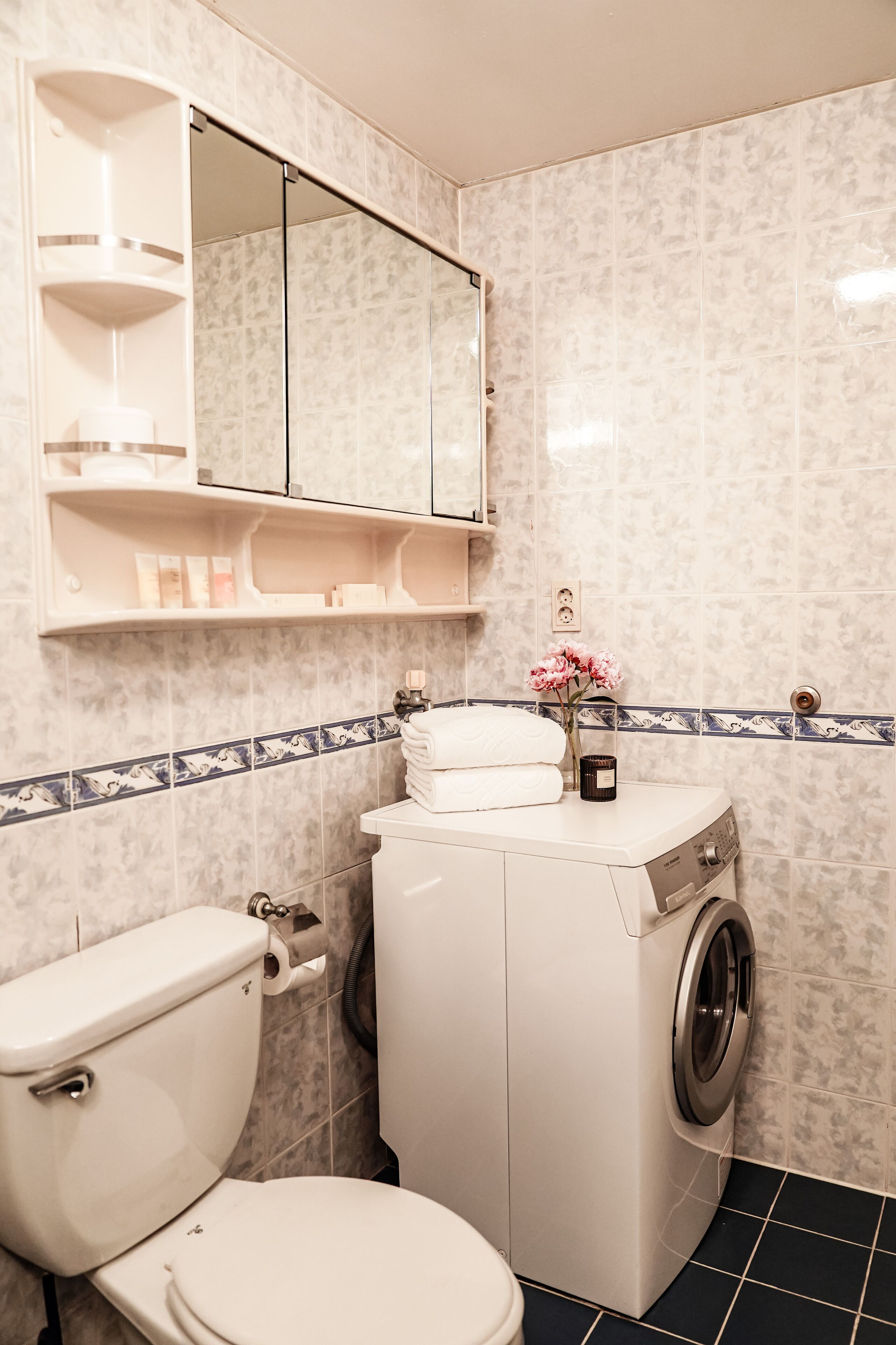 Un baño con inodoro, lavadora y espejo sobre el lavabo.