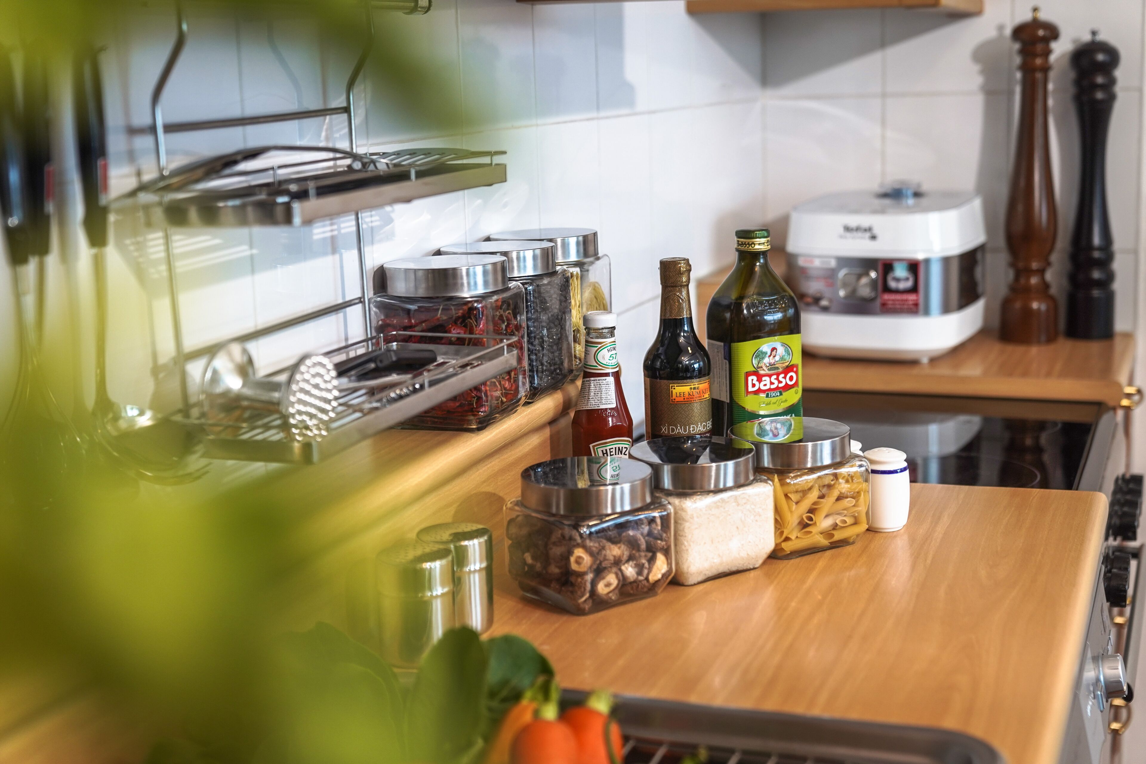 A kitchen counter with various condiments, a bottle of Basso wine, and a rice cooker.