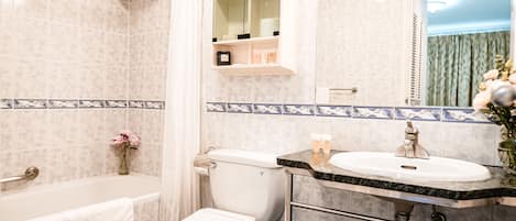 A bathroom with a bathtub, toilet, sink, and a mirror.