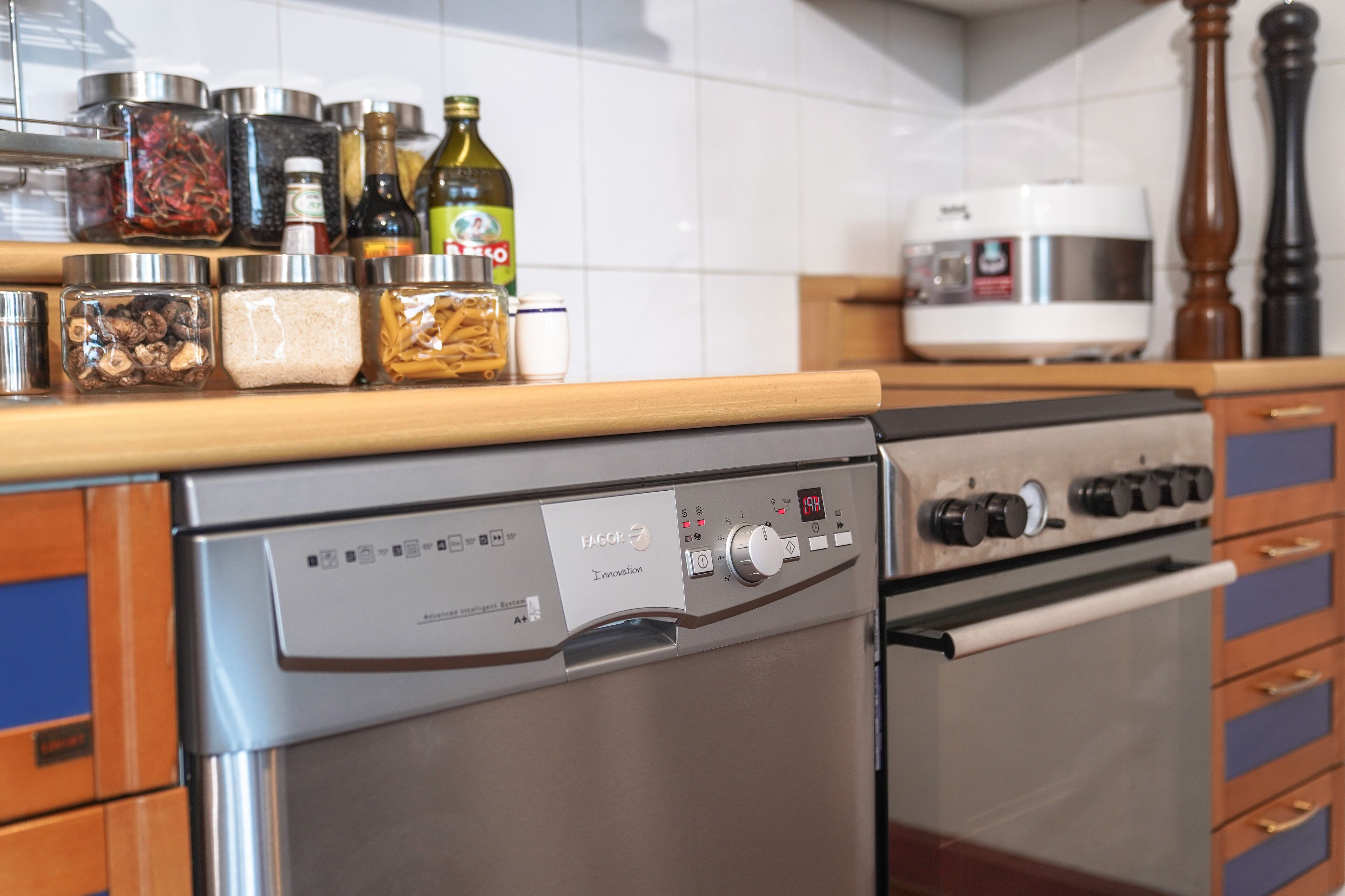 A kitchen with a stainless steel dishwasher and oven, a wooden countertop, and various kitchen items.