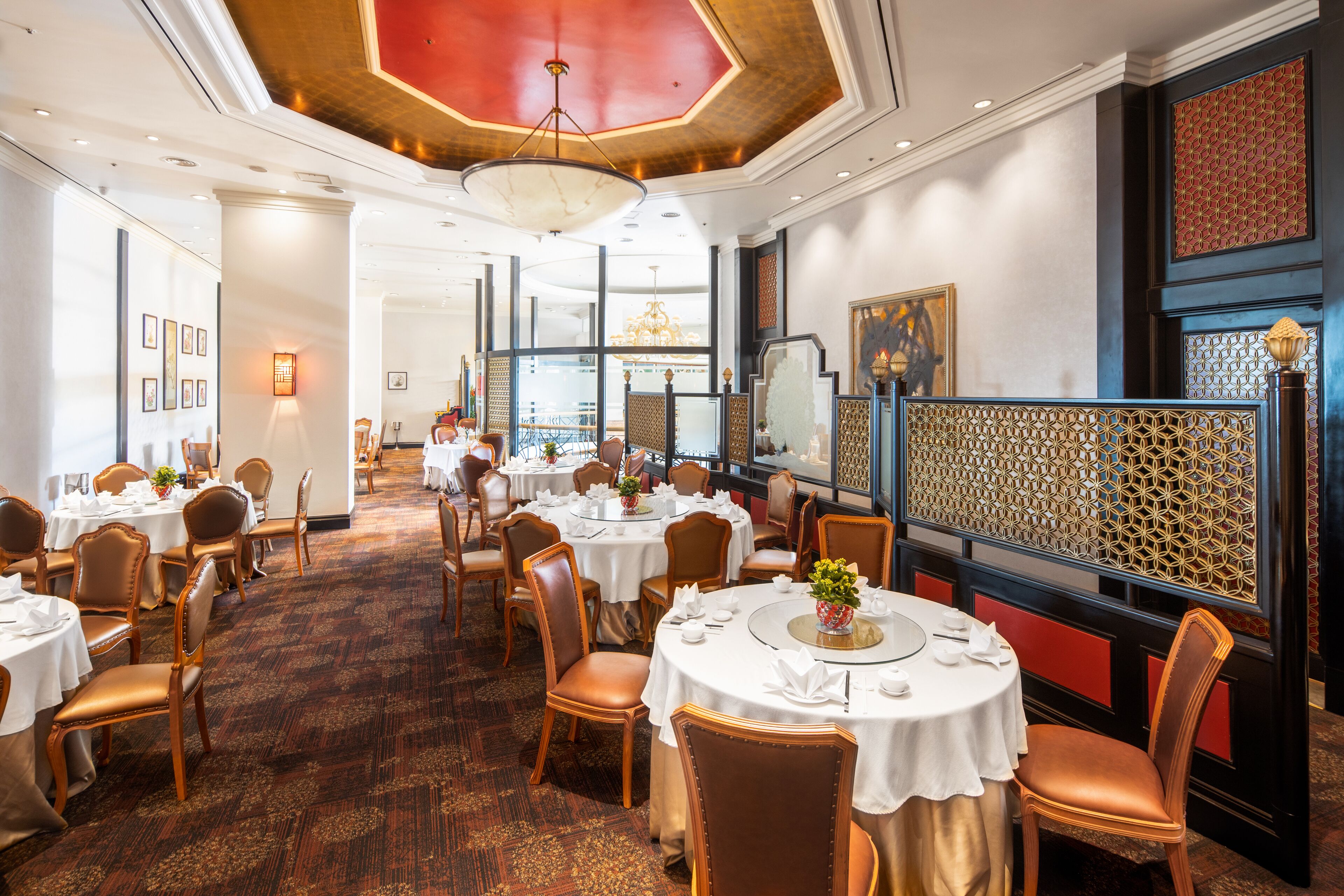 A dining area with round tables and chairs, a patterned carpet, and a decorative wall.