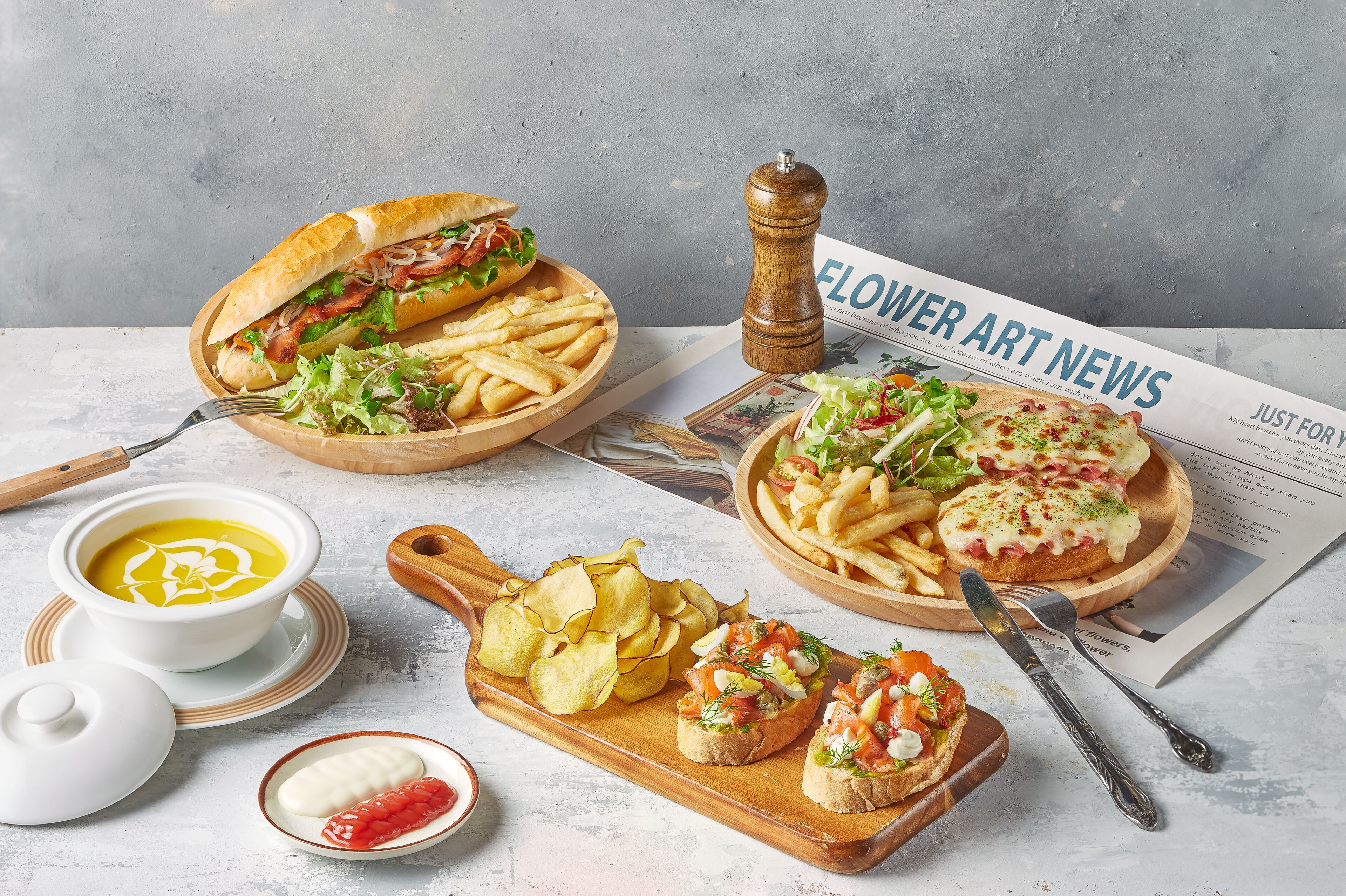 A table with various food items including a sandwich, fries, chips, soup, and toast.