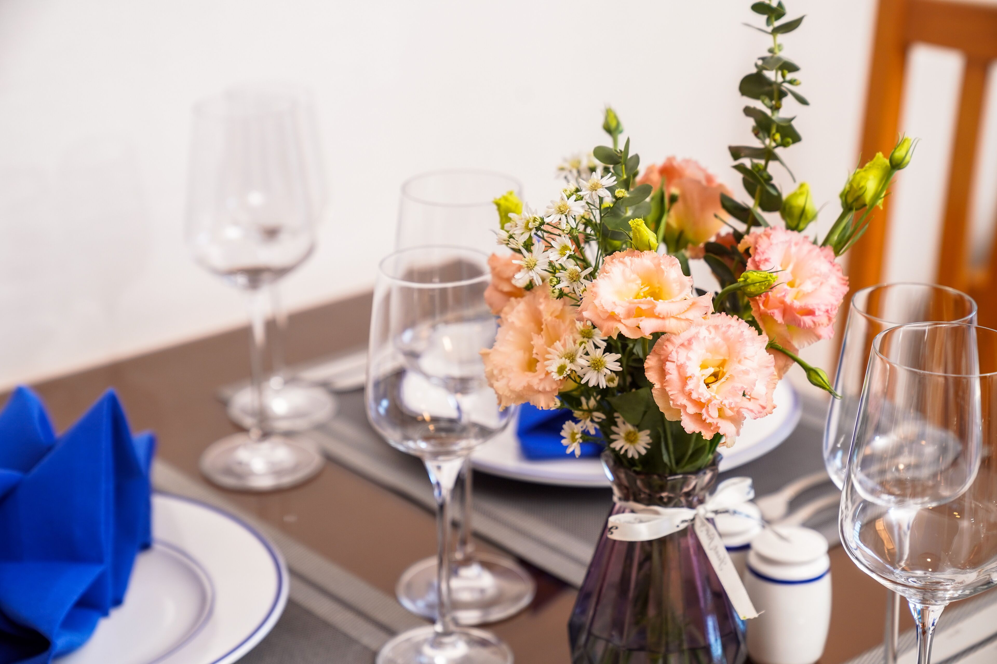 Una mesa de comedor dispuesta con platos, vasos y un florero.