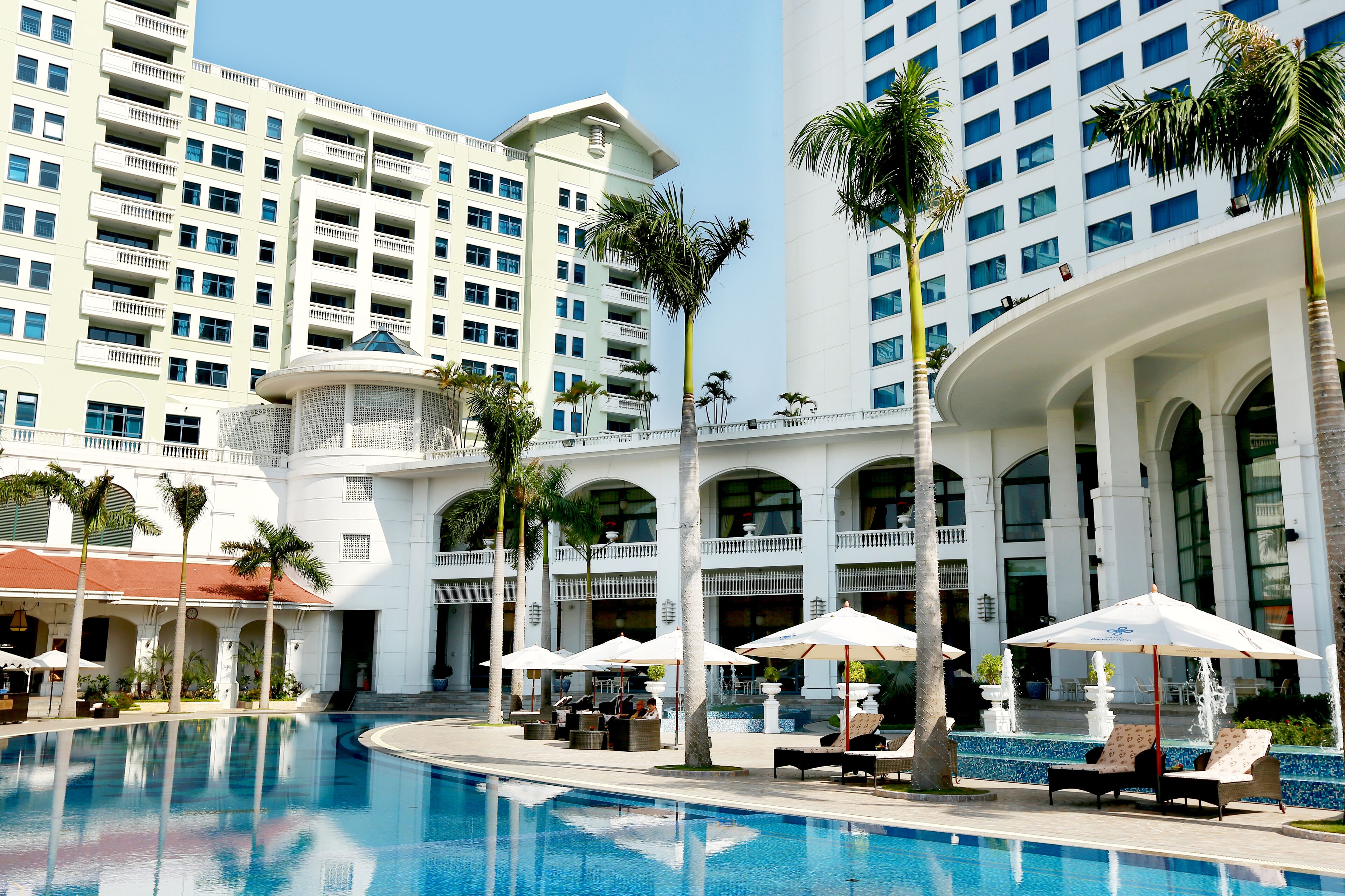 A hotel pool area with lounge chairs and umbrellas, surrounded by tall buildings.