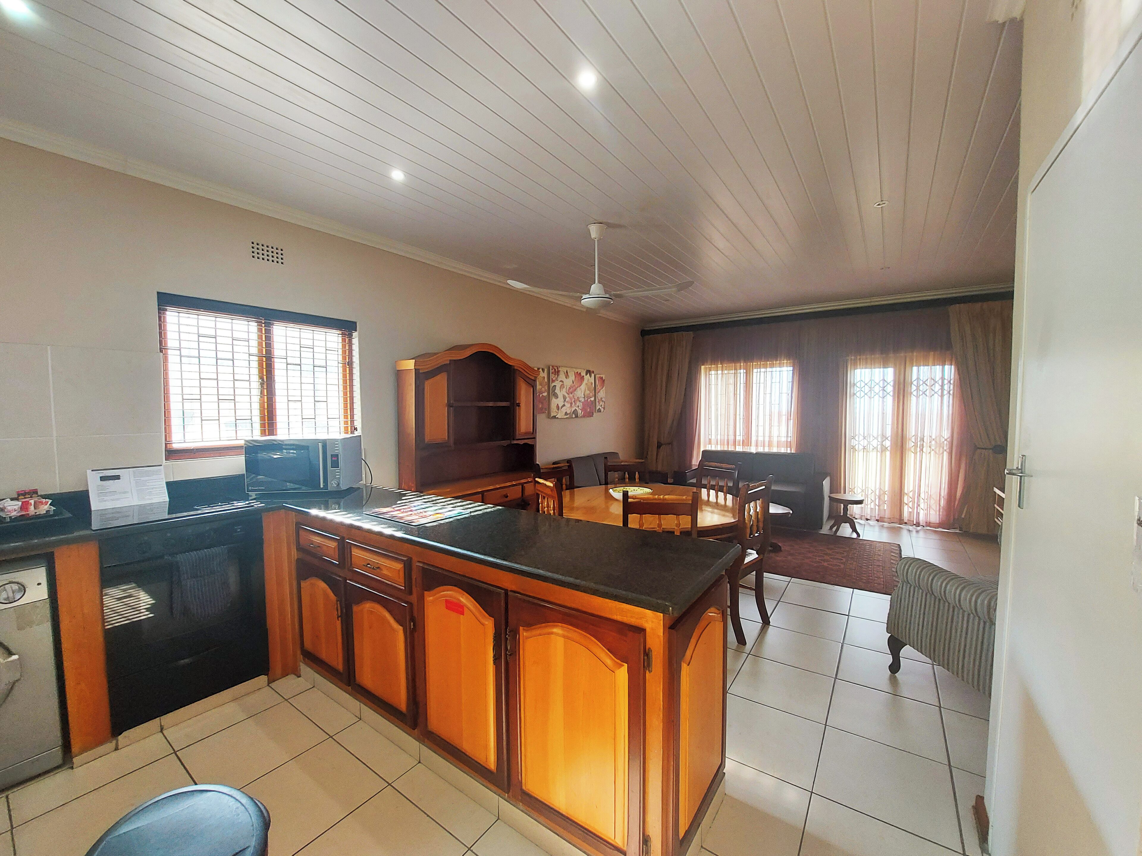 A spacious kitchen with a central island, wooden cabinets, a microwave, and a dining area with a table and chairs.