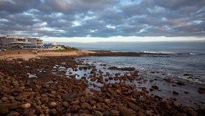 Une plage de galets avec un bâtiment en arrière-plan.