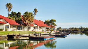 A waterfront hotel with red roofs, a dock, and calm water reflecting the buildings. - First Group Port Owen Marina (Bergrivier)