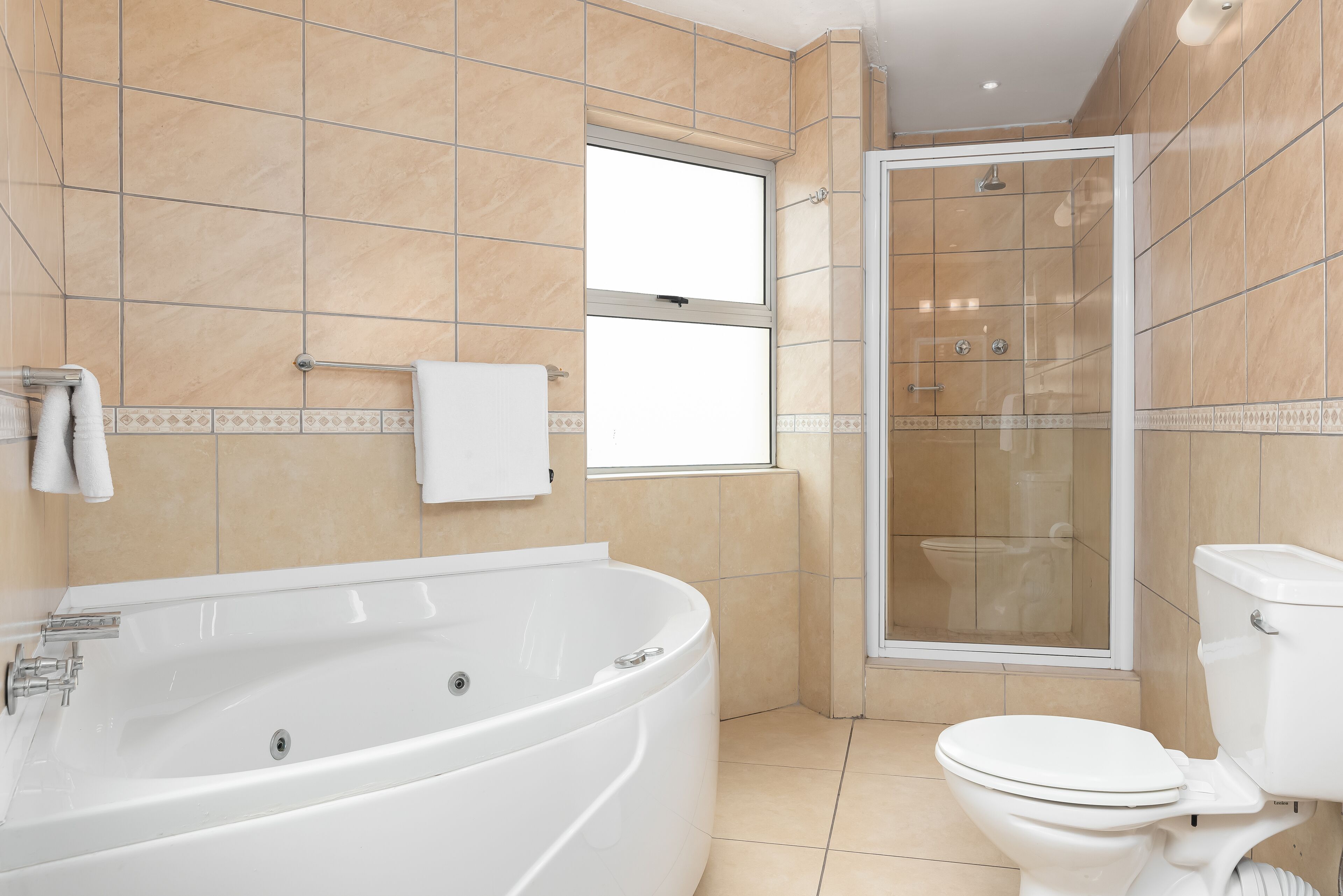 A modern bathroom with a large bathtub, a glass-enclosed shower, and a toilet.