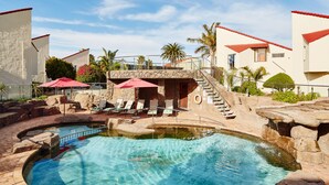 A pool area with a stone structure, lounge chairs, and umbrellas. - First Group Port Owen Marina (Bergrivier)